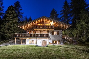 A large house with a wooden roof is lit up at night