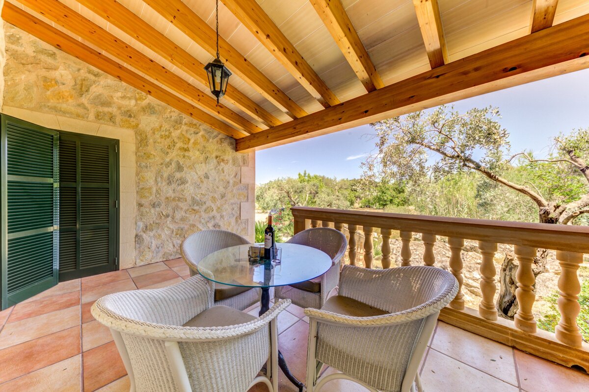 A balcony with wicker chairs and a glass table
