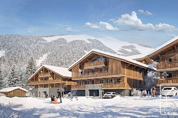 A snowy alpine village featuring large wooden chalets, people playing in fresh snow, cars, and majestic snow-covered mountains and forests under a blue sky.