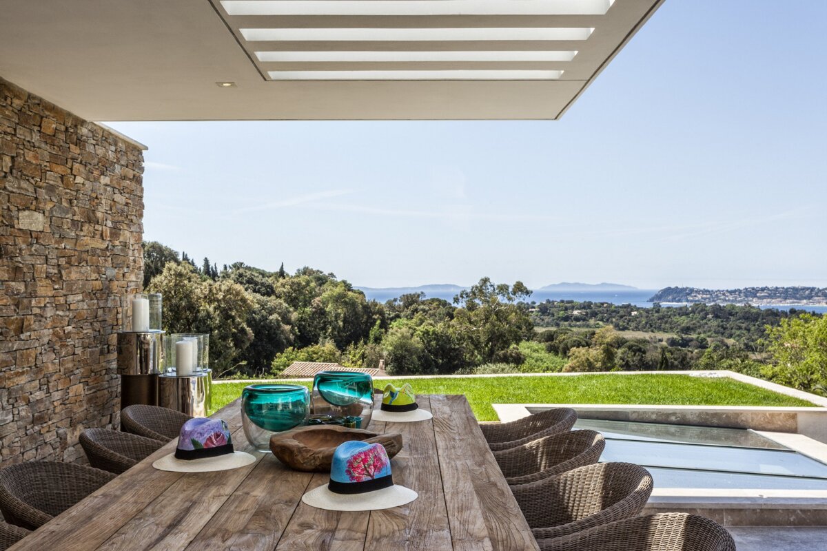 A wooden table with wicker chairs and a view of the ocean