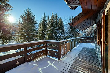 A balcony with snow on it and trees in the background