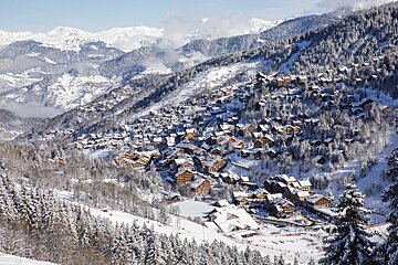 A snowy mountain landscape with a ski resort in the foreground
