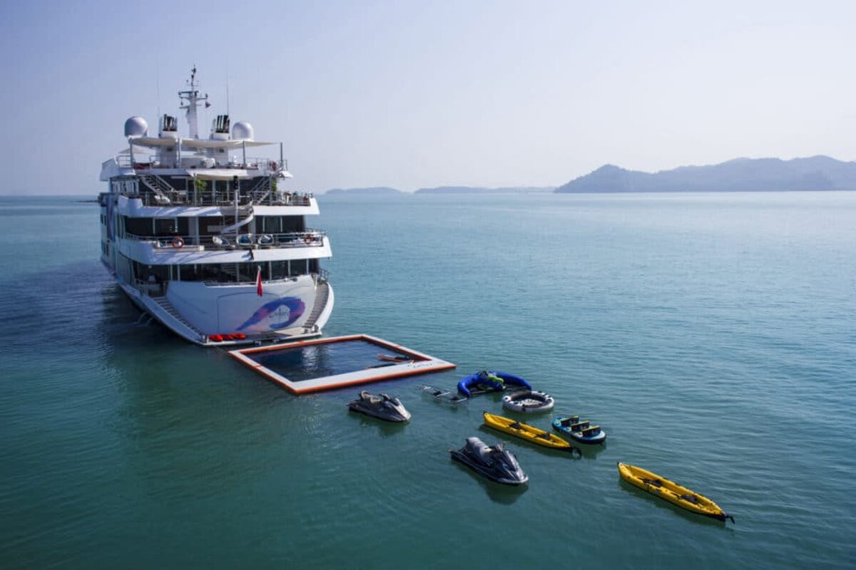 A large yacht with jet skis and kayaks in front of it
