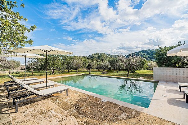 A swimming pool surrounded by chairs and umbrellas on a sunny day
