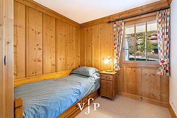 A bedroom with a single bed and a nightstand with the letters vjp on the bottom