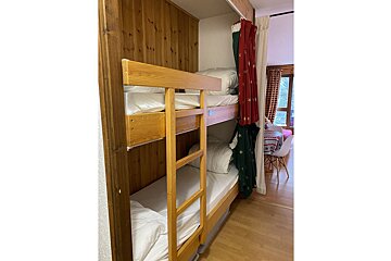 A bunk bed with a green curtain behind it