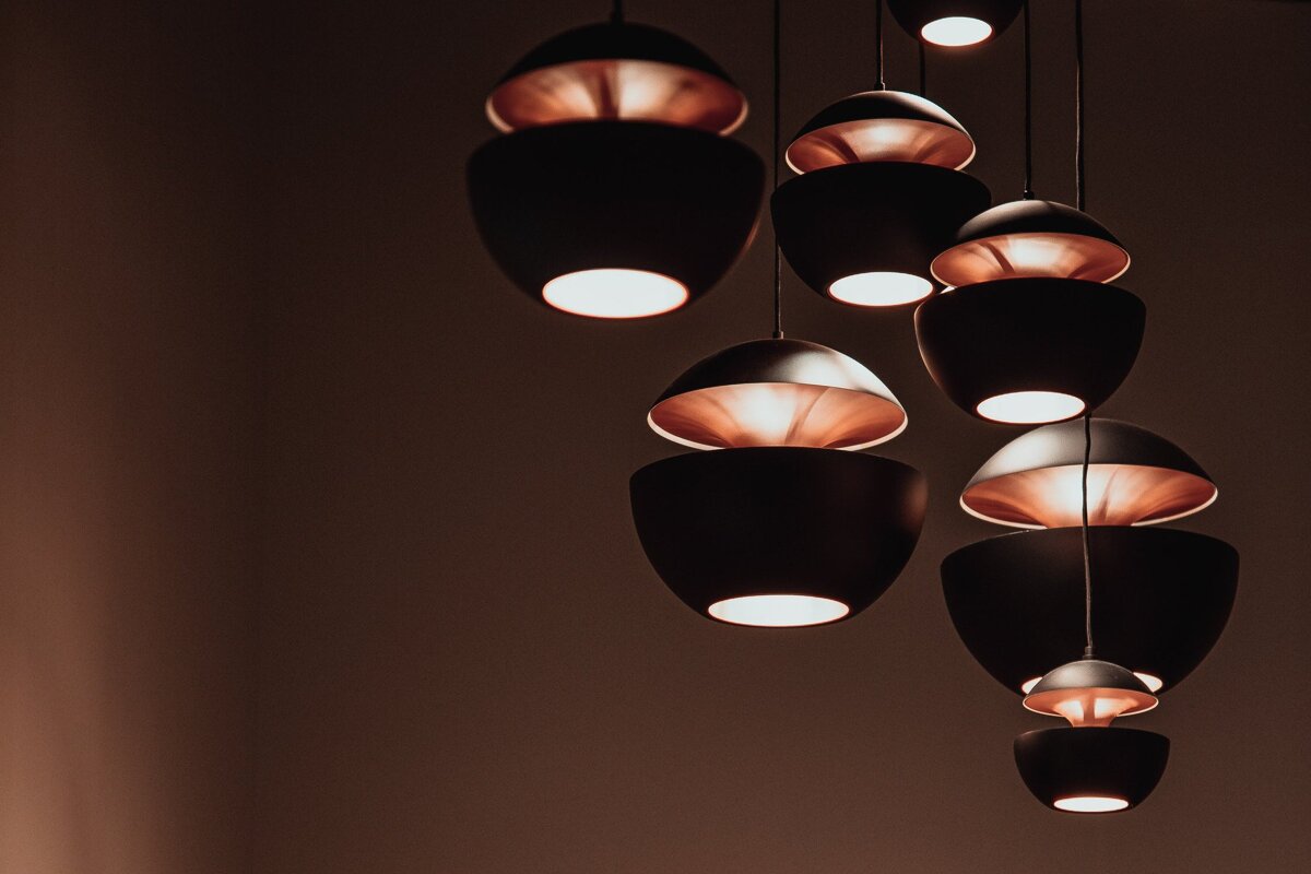 Modern black pendant lights with glowing copper-colored interiors hanging in a cluster.