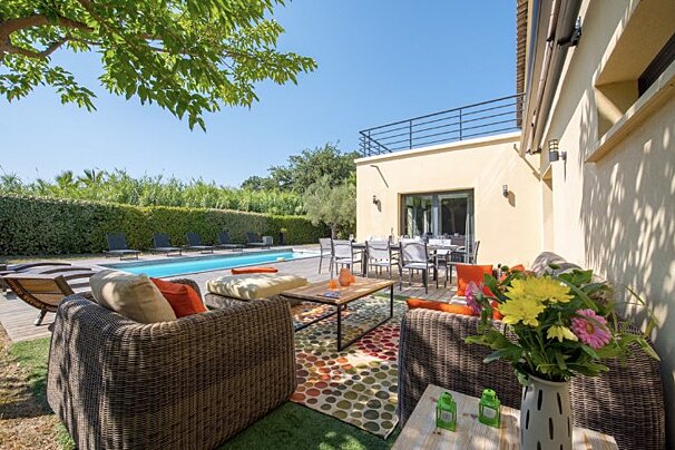 A patio area with a couch and a vase of flowers