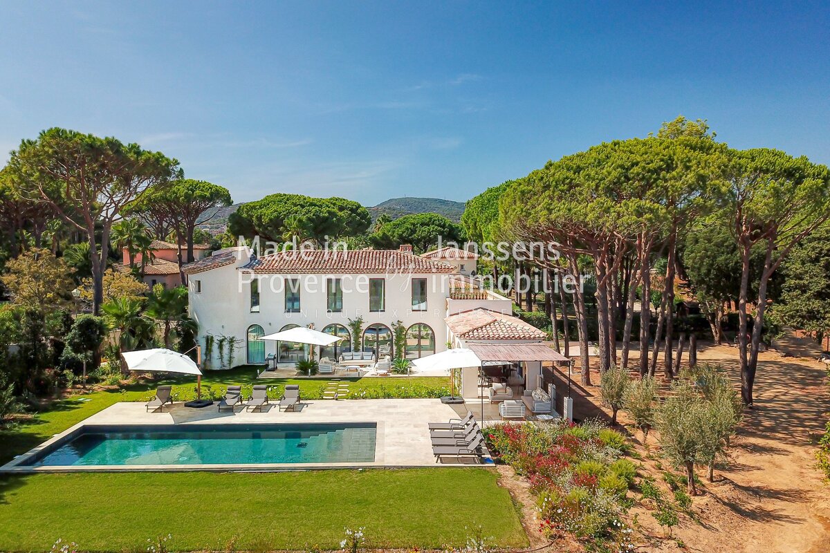 An aerial view of a large white house with a large swimming pool