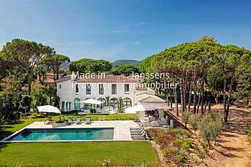 An aerial view of a large white house with a large swimming pool