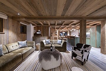 A living room with a cow print chair and a couch