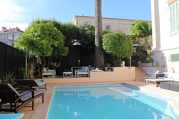 A large swimming pool surrounded by chairs and trees