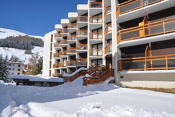 A building with a lot of balconies is covered in snow