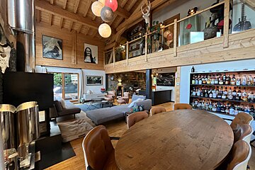 Spacious, rustic-modern chalet interior featuring a dining area, lounge, mezzanine, and a vast liquor collection.