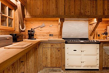A kitchen with a white aga stove and wooden cabinets