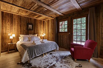 A bedroom with a large bed and a red chair