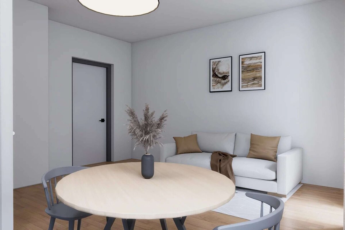 A modern, minimalist open-concept living space with a round wooden dining table, white sofa, abstract art, and light wood flooring.