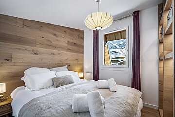 A green chair sits on a balcony overlooking a ski resort