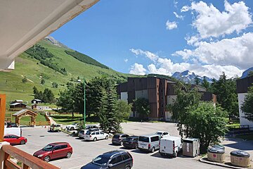 A view of a parking lot with cars parked and mountains in the background