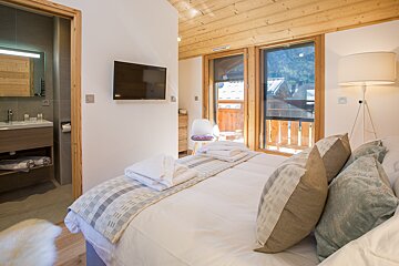 A bedroom with a large bed and a flat screen tv