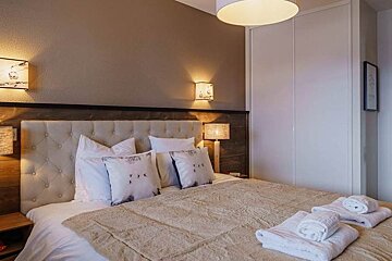 A bedroom with a bed and lamps and a picture on the wall