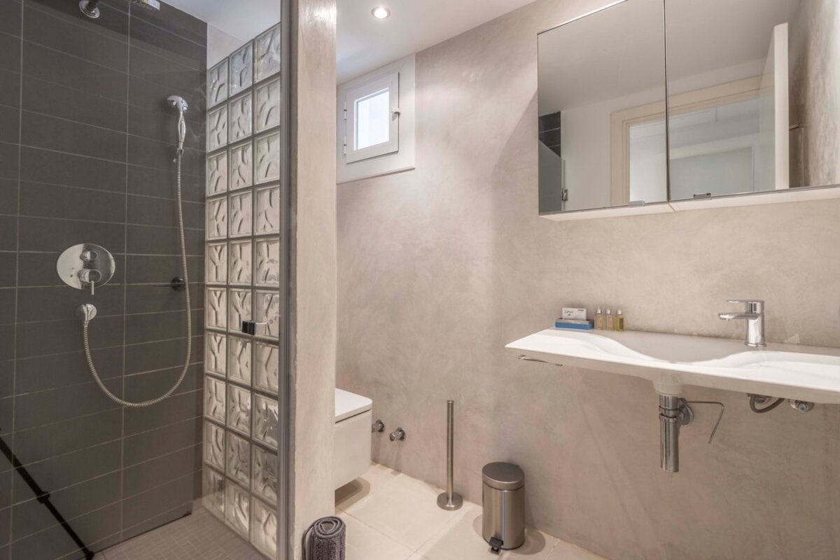 A bathroom with a walk in shower and a sink