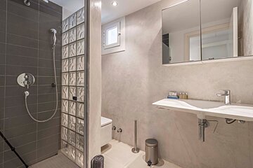 A bathroom with a walk in shower and a sink