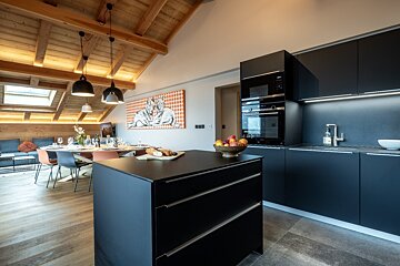 A kitchen with black cabinets and a large island in the middle
