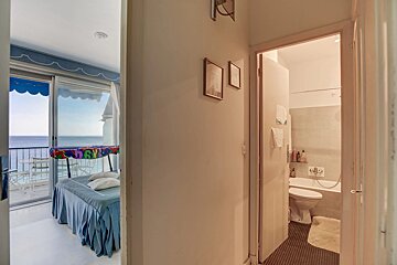 A hallway view of a bedroom with an ocean-view balcony on the left and a bathroom on the right.