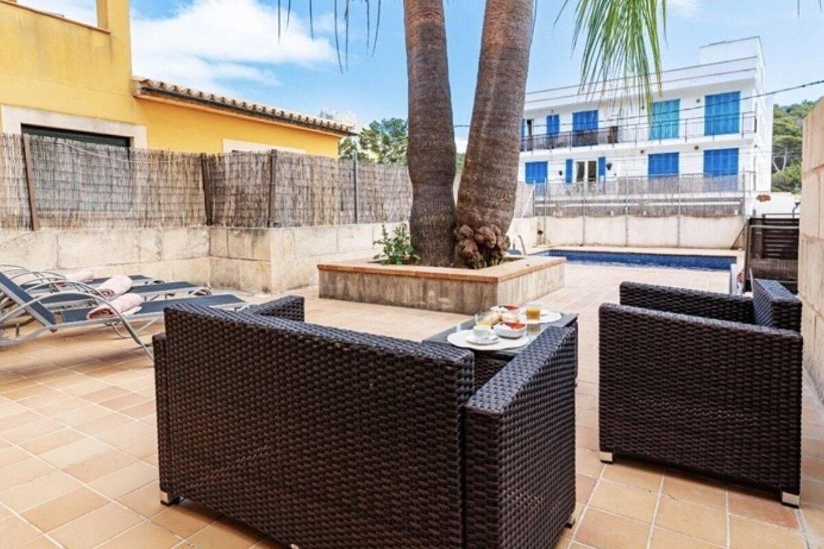 A patio with chairs and a table with plates of food on it