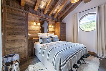 A bedroom with a bed and a round window