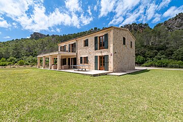 A large stone house with a large lawn in front of it