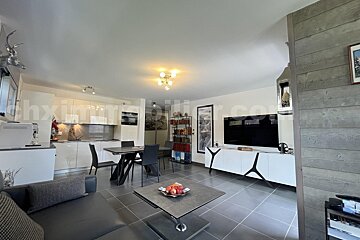 A living room with a couch a table and a television with the words thximmobilier.com on the bottom