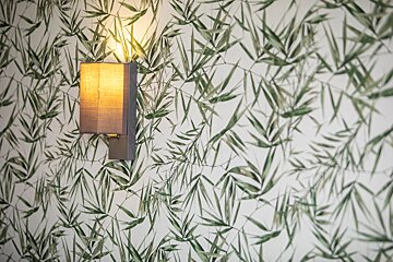 A wall with green leaves on it and a lamp on it