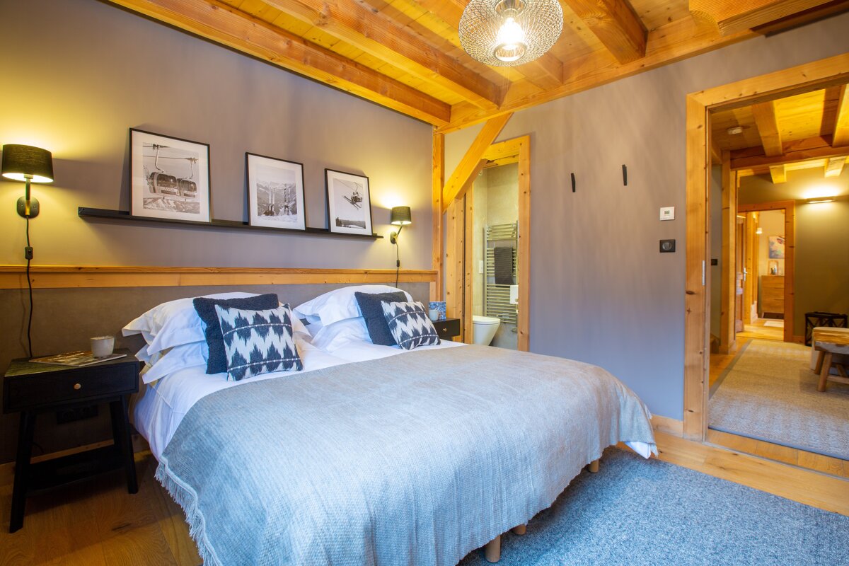 A bedroom with a bed and a shelf with pictures on it