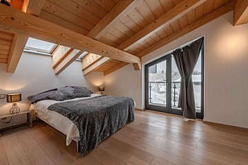 A bedroom with a bed and a window with a skylight