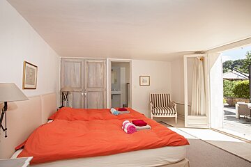 A bedroom with two beds and a striped chair
