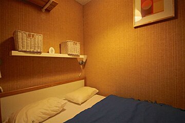A bedroom with a bed and two baskets on a shelf