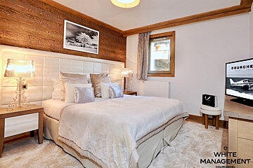 A bedroom with a large bed and a tv that says courchevel