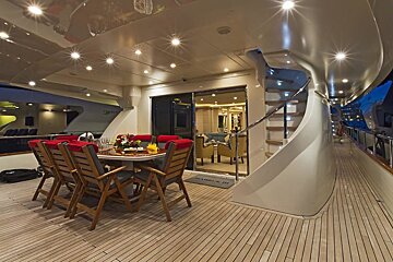 A yacht deck with a table and chairs and a welcome mat