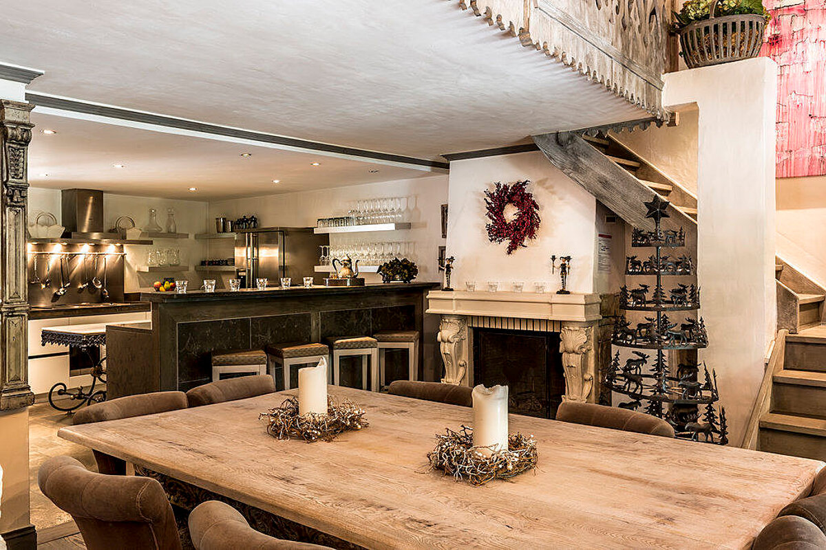 A wooden table with two candles on it in front of a fireplace