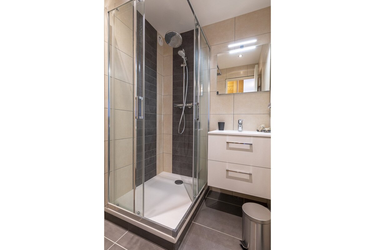 A bathroom with a walk in shower and a sink