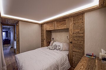 A bedroom with a white bed and wooden walls