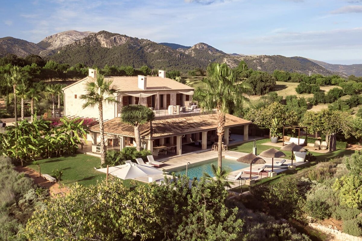 A swimming pool with chairs under an orange umbrella