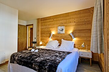 A bedroom with a painting of a skier on the wall above the bed