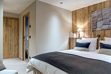 A bedroom with a large bed and a wooden wall