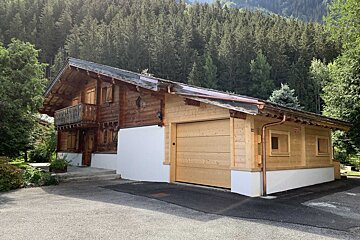 A small wooden house with a garage and a balcony
