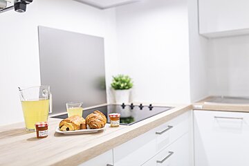 A kitchen counter with a pitcher of lemonade croissants and jars of jam