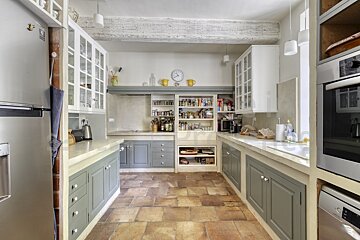 A kitchen with white cabinets and a clock on the wall