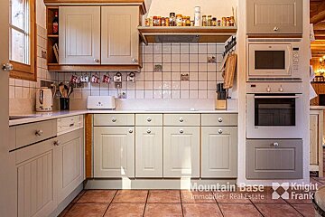 A kitchen with white cabinets and a knight frank logo
